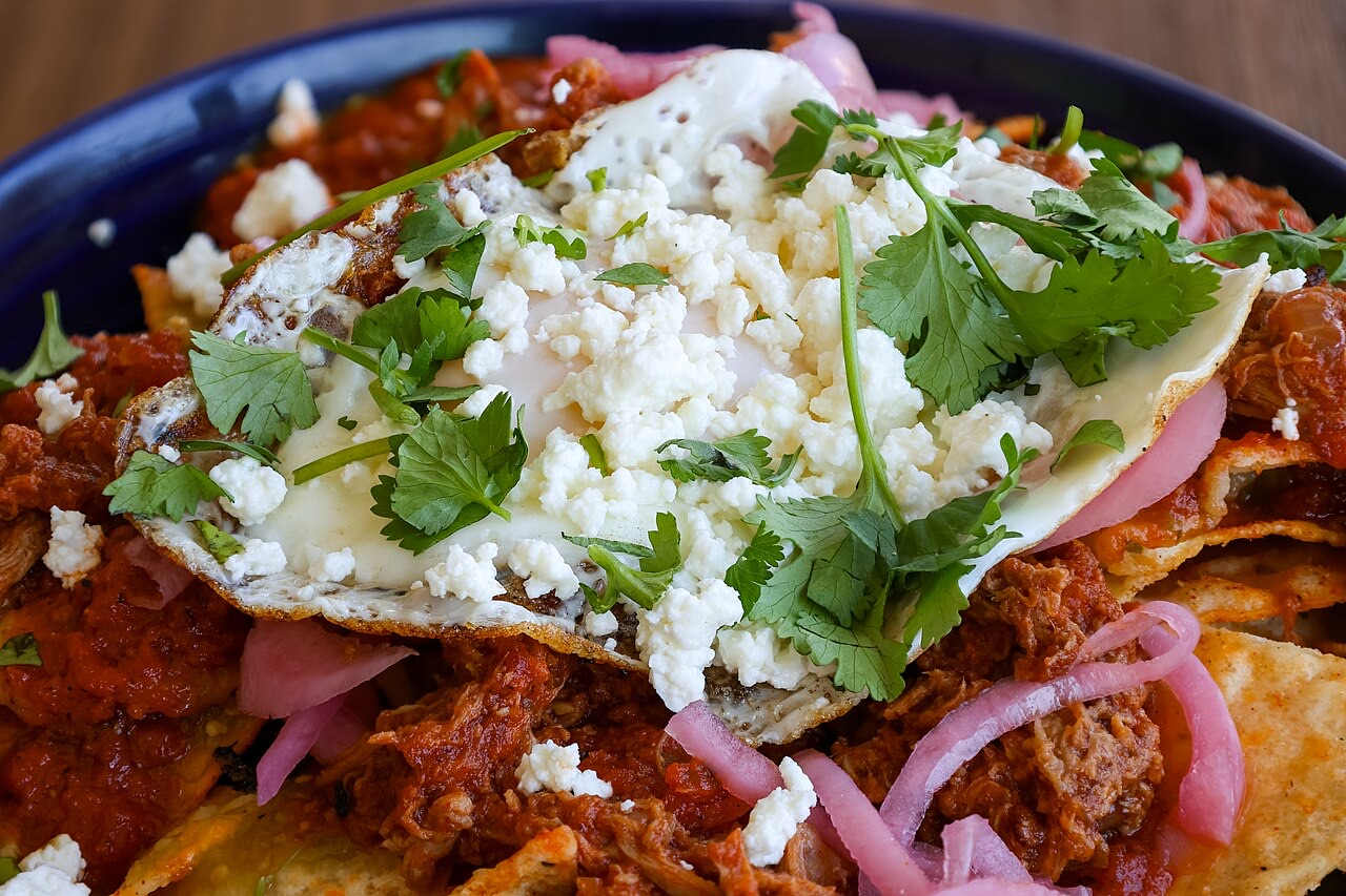 A plate of chilaquiles topped with a fried egg, queso fresco, and cilantro, a classic Mexican breakfast