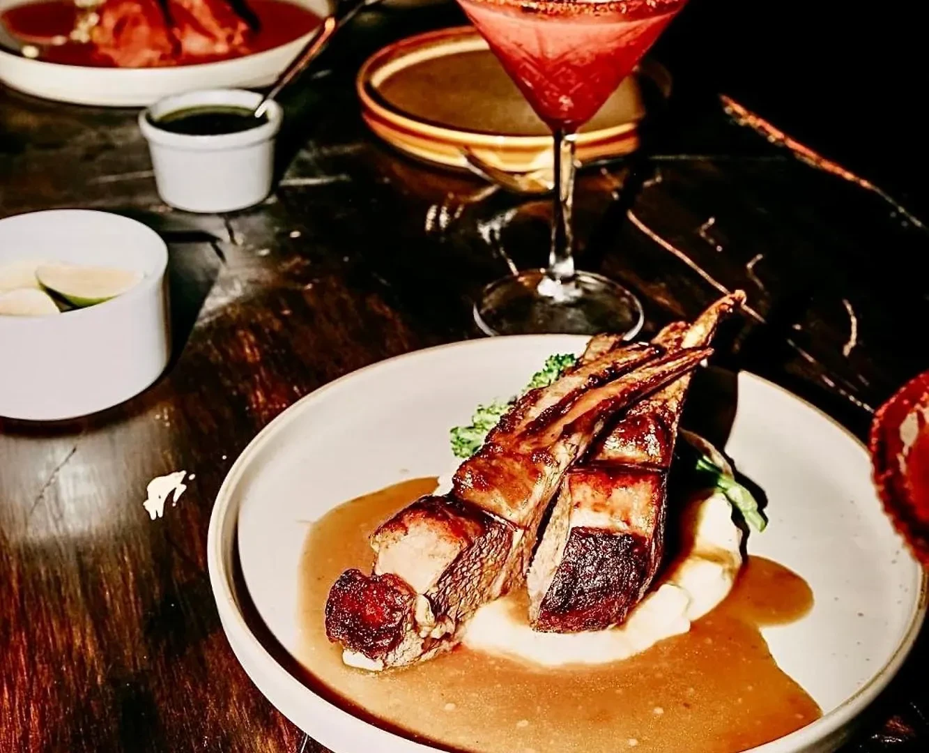 Grilled lamb chops over potato purée with jus and a cocktail