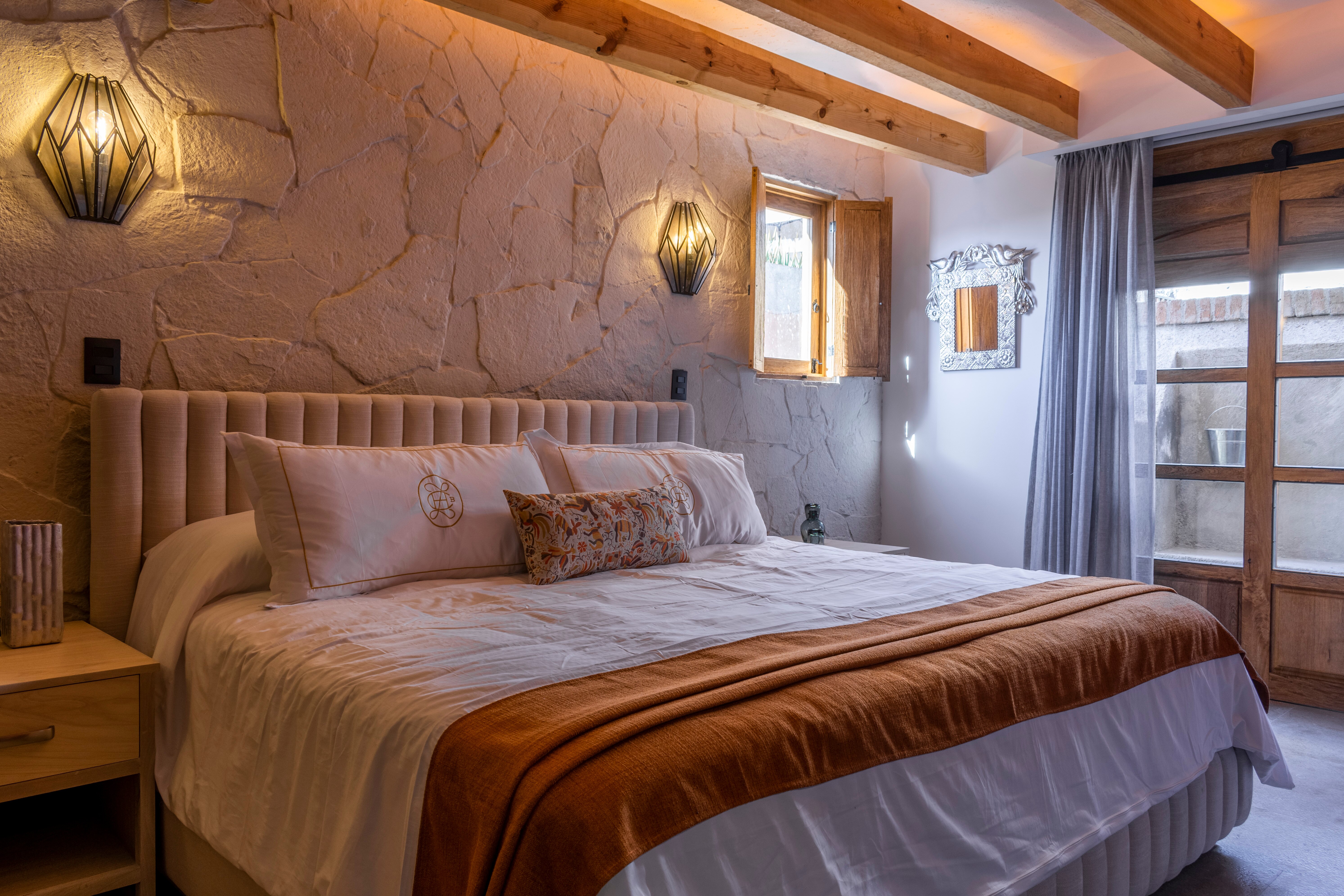 King bed with tufted headboard against a stone wall