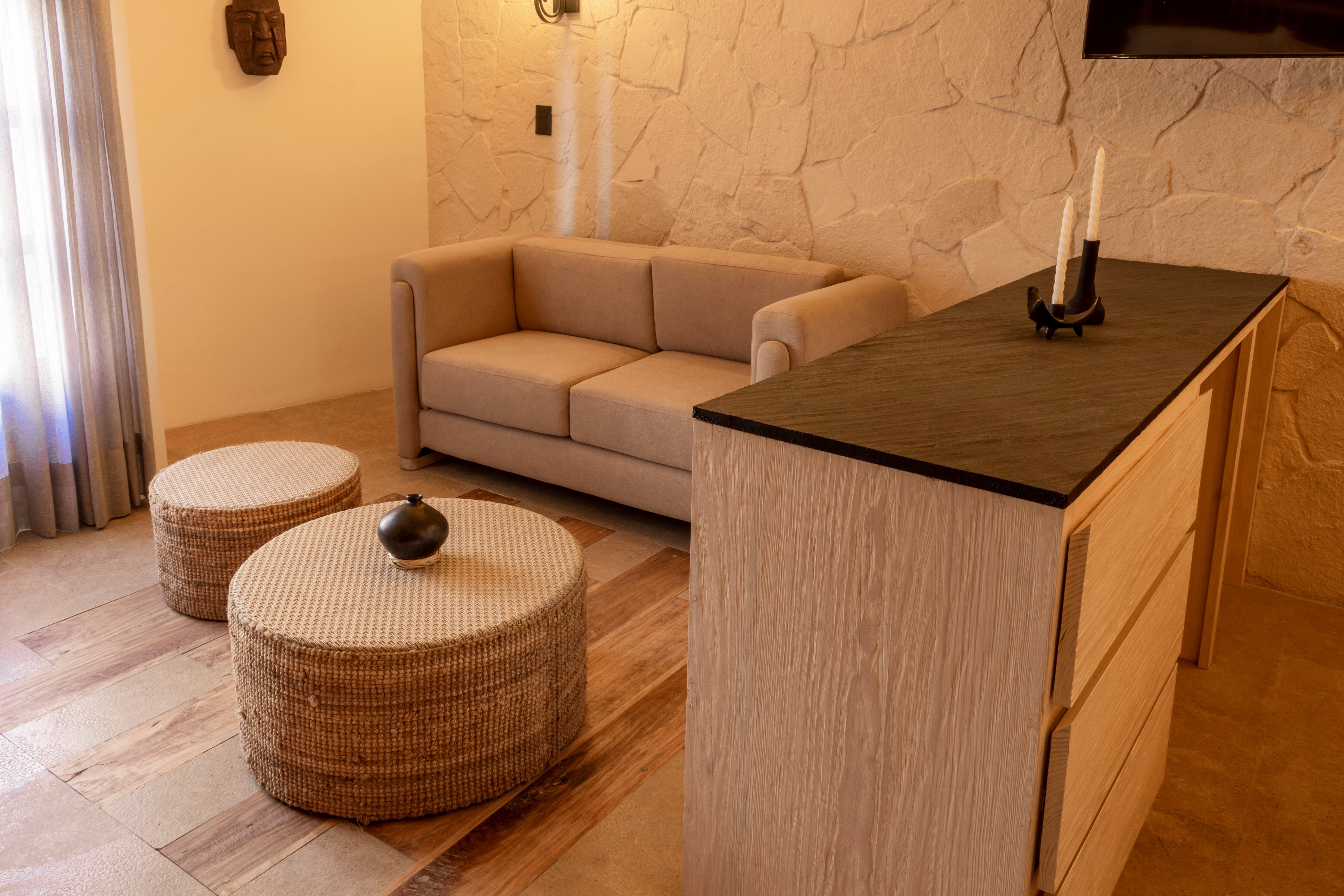 Suite living area with sofa, woven ottomans, and a stone wall