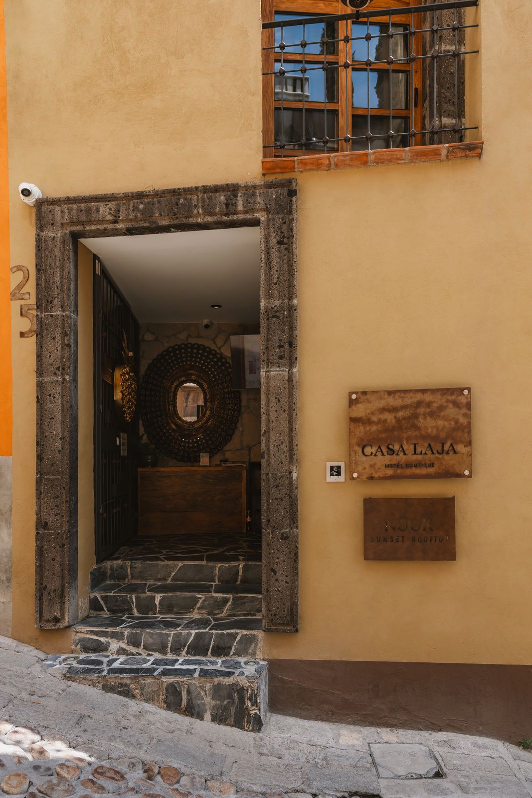 The Casa Laja doorway open onto a cobblestone street, with the engraved wooden nameplate beside it