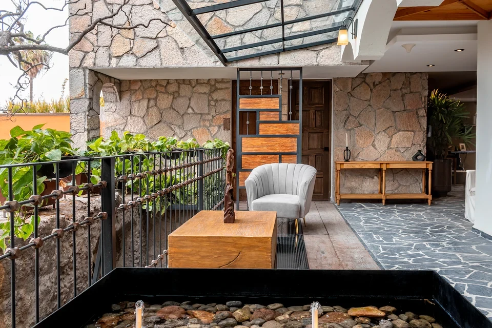 Covered terrace with a koi pond, armchair, and stone walls