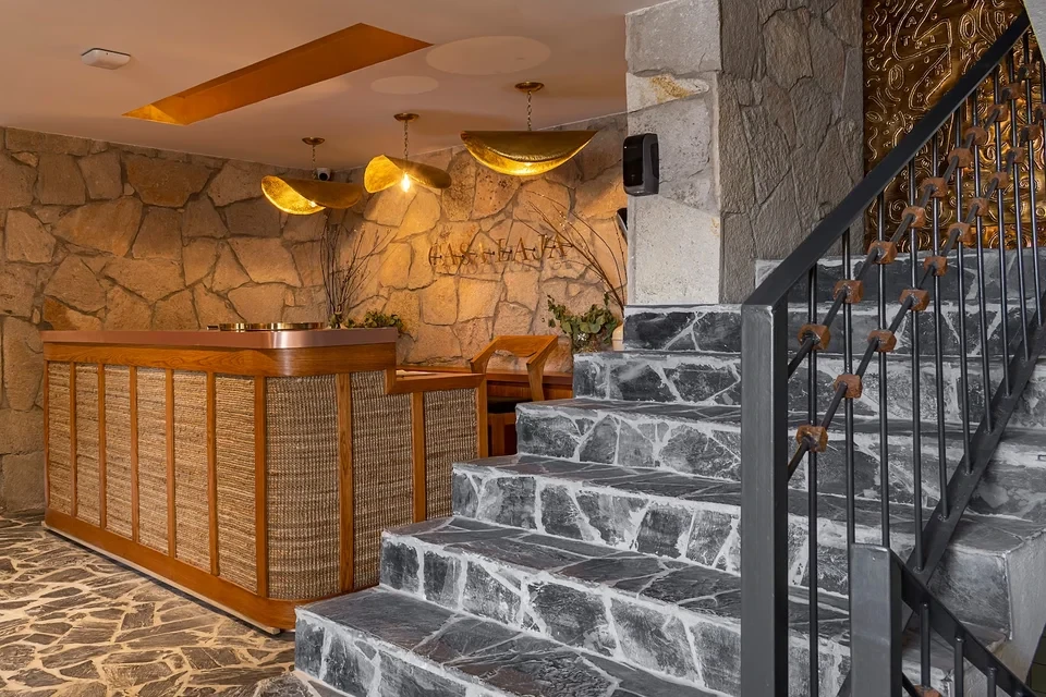 Reception desk in woven wood and stone beside the stone staircase
