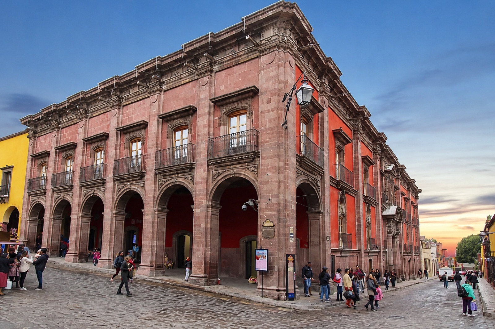 The arcaded pink-stone facade of the historic Casa del Mayorazgo de la Canal on a cobblestone street in San Miguel de Allende